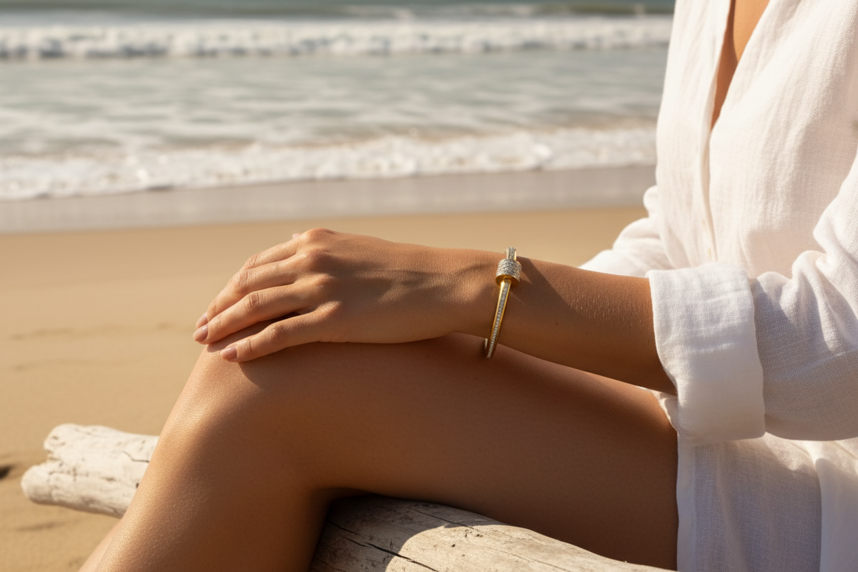 Gold nail bangle on woman's wrist at the beach